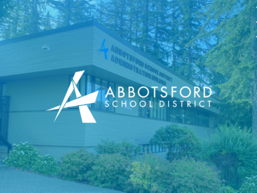 Light blue overlay of a picture with the school board office in the background with the logo in the center.