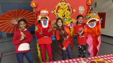 Students dressed in red and wearing or holding items to celebrate Lunar New Year.